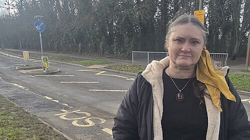 Councillor Andrew Bowes standing in front of a road full of pot holes